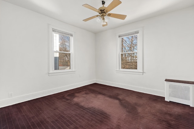 unfurnished room featuring ceiling fan, radiator, and dark wood-type flooring