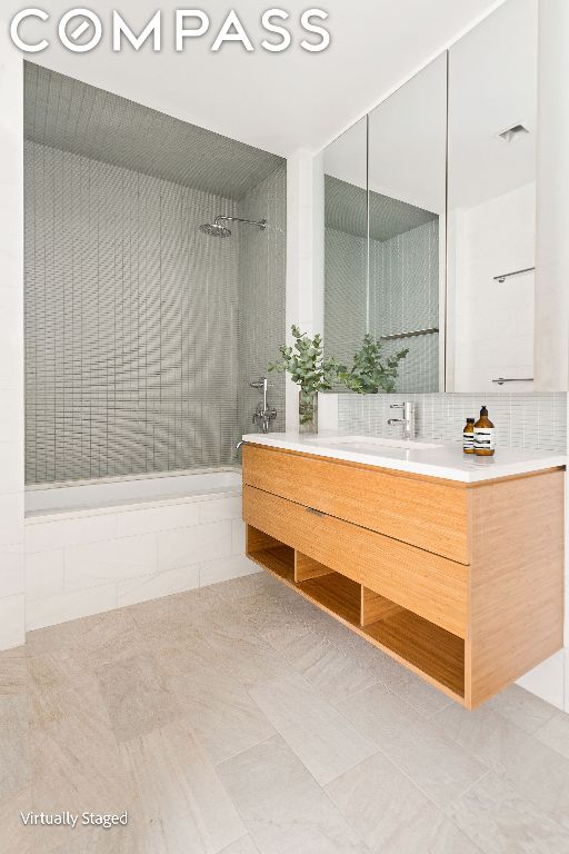 bathroom featuring tiled shower / bath combo, backsplash, and vanity