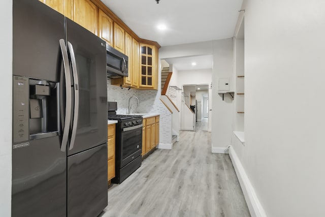 kitchen featuring range with gas cooktop, decorative backsplash, black refrigerator with ice dispenser, light hardwood / wood-style flooring, and sink