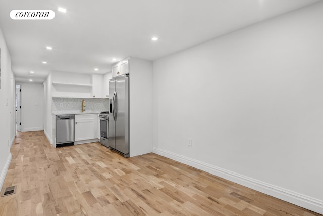 kitchen with tasteful backsplash, sink, light hardwood / wood-style flooring, stainless steel appliances, and white cabinets