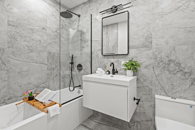 full bathroom featuring toilet, vanity, tile walls, tile patterned floors, and tiled shower / bath combo