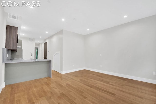 unfurnished living room featuring sink and light hardwood / wood-style flooring