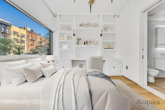 bedroom featuring light wood-style flooring and ensuite bath
