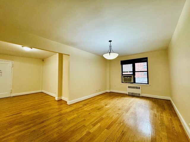 empty room with radiator, cooling unit, and wood-type flooring