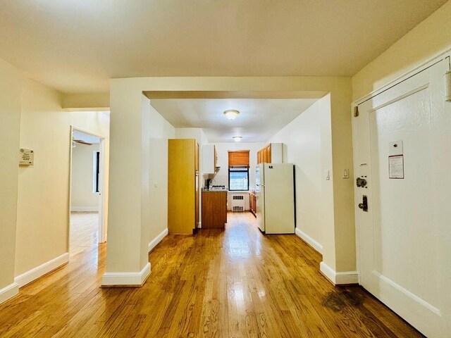 corridor with radiator heating unit and light hardwood / wood-style flooring