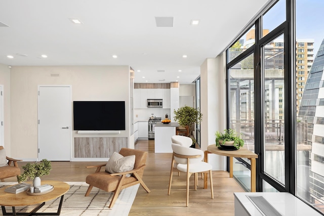 living room featuring light wood-type flooring, expansive windows, and recessed lighting