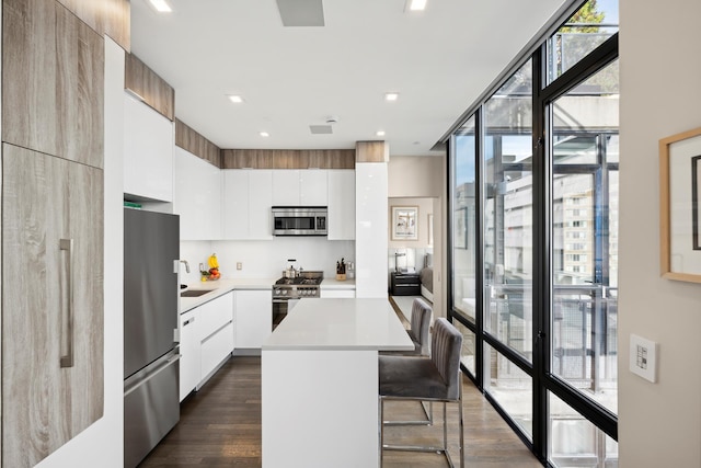 kitchen with light countertops, appliances with stainless steel finishes, a kitchen bar, modern cabinets, and a center island