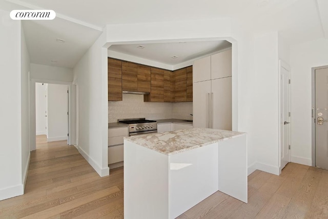 kitchen featuring white cabinetry, high end stove, light hardwood / wood-style floors, and a kitchen island