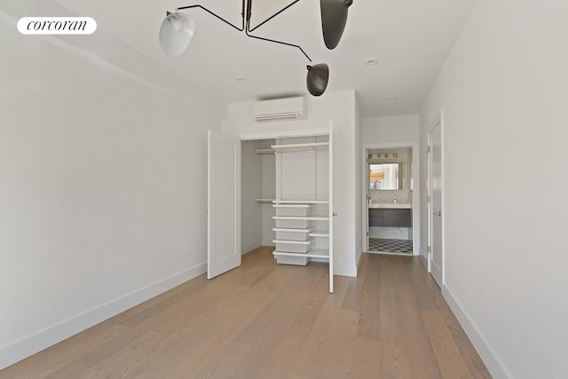 unfurnished bedroom with wood finished floors, visible vents, baseboards, a closet, and a wall mounted AC