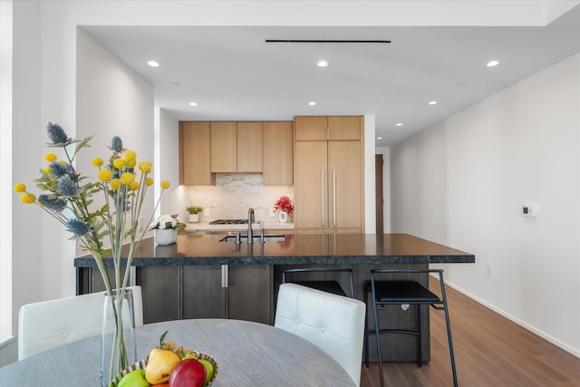 kitchen featuring a sink, dark wood finished floors, tasteful backsplash, a kitchen breakfast bar, and recessed lighting
