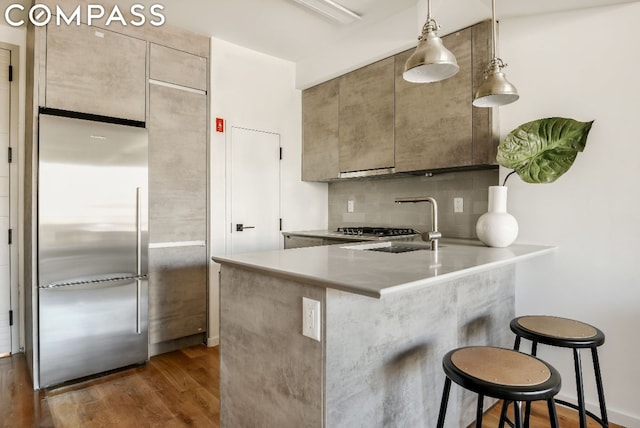 kitchen featuring tasteful backsplash, kitchen peninsula, dark hardwood / wood-style flooring, a breakfast bar area, and stainless steel fridge