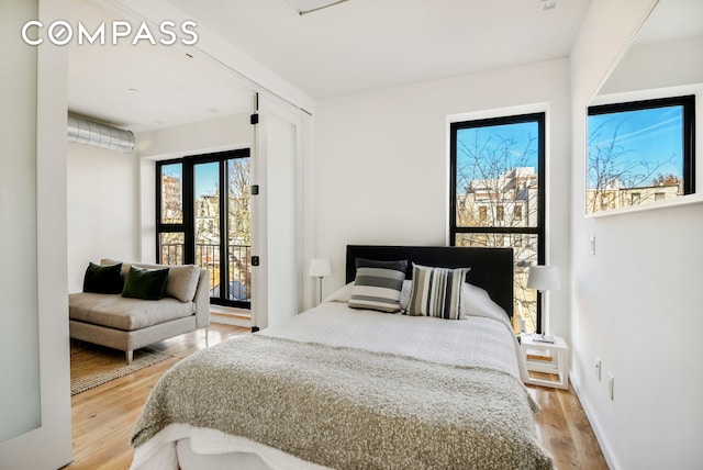 bedroom featuring baseboards, access to outside, and light wood finished floors