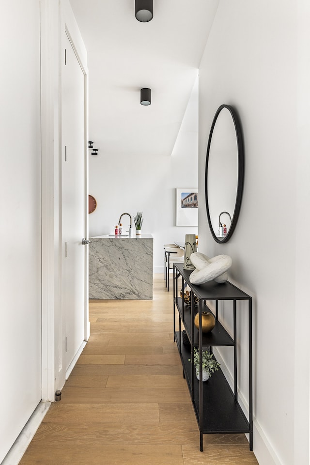 corridor with light wood-type flooring and baseboards