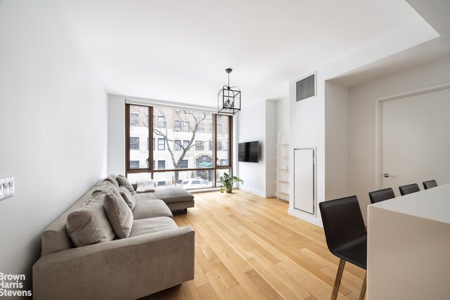 living room featuring hardwood / wood-style floors, a wall of windows, and a chandelier