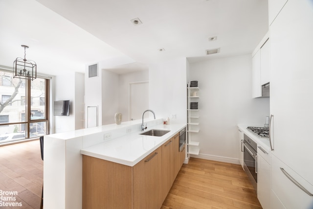 230 E 20th St Unit 23, New York City, NY 10003 - kitchen featuring a peninsula, light wood-style flooring, appliances with stainless steel finishes, light countertops, and modern cabinets