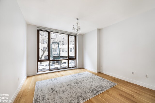 empty room with an inviting chandelier and hardwood / wood-style flooring