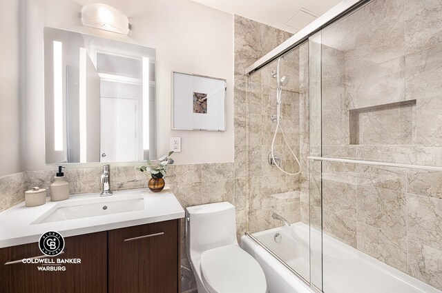 full bathroom featuring toilet, vanity, and shower / bath combination with glass door