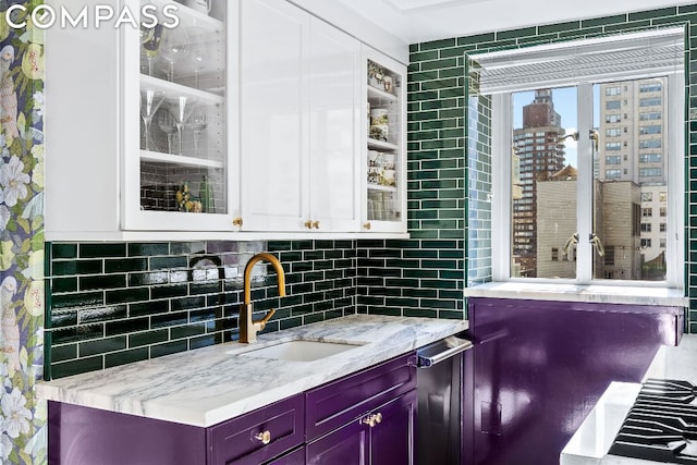 bar featuring white cabinetry, sink, decorative backsplash, and light stone countertops