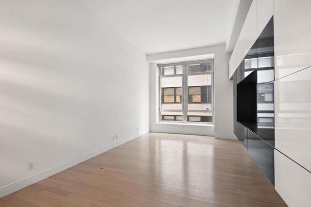 empty room with light wood-type flooring and baseboards