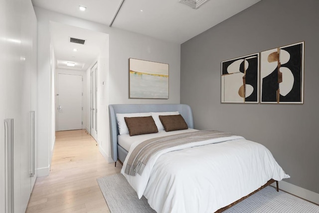 bedroom with visible vents, light wood-style flooring, and baseboards