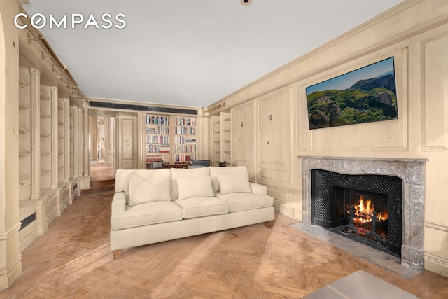 1 E 62nd St Ph, Ph, New York City, NY 10065 - living area with ornamental molding, a premium fireplace, built in features, and a decorative wall