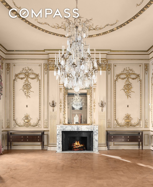 unfurnished living room with a premium fireplace, an inviting chandelier, and ornamental molding