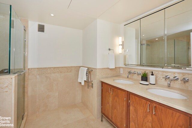 200 E 66th St Unit B1804, New York City, NY 10065 - full bathroom featuring a stall shower, double vanity, wainscoting, tile walls, and tile patterned flooring