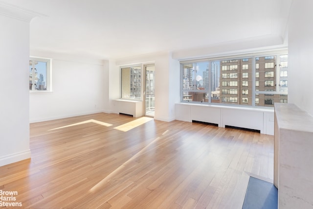 unfurnished living room with light wood-type flooring and baseboards