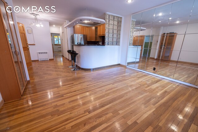 interior space featuring radiator heating unit, light hardwood / wood-style floors, and a chandelier