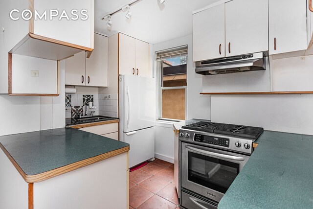 kitchen with sink, stainless steel range with gas stovetop, white cabinetry, a healthy amount of sunlight, and white refrigerator