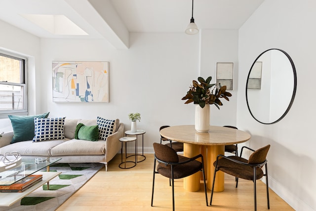 dining room with light hardwood / wood-style flooring and beamed ceiling