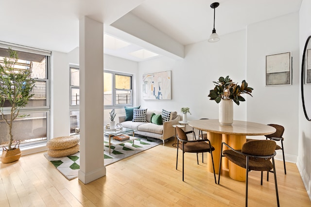 dining area featuring light wood-type flooring, a wealth of natural light, and floor to ceiling windows