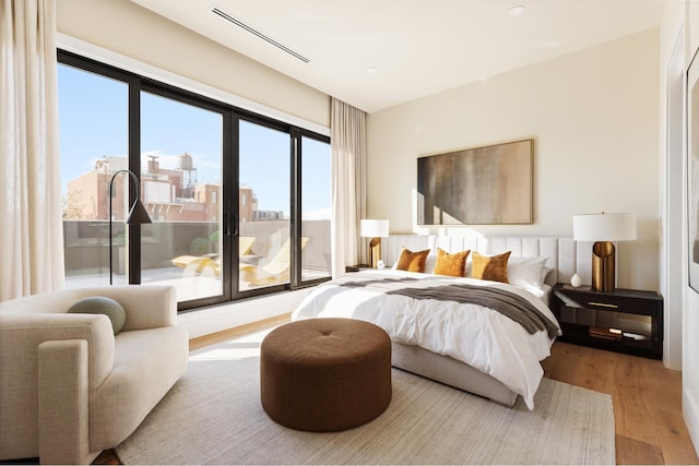 bedroom featuring access to outside, visible vents, and wood finished floors