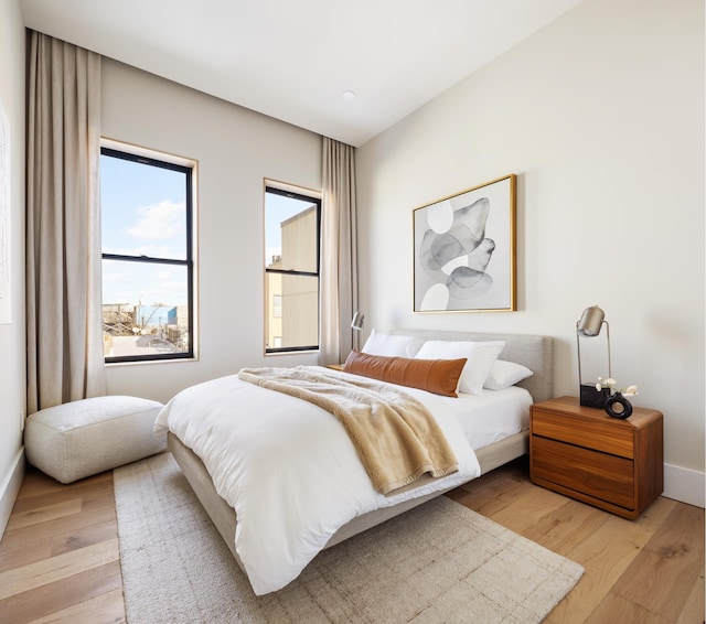 bedroom featuring light wood finished floors and baseboards