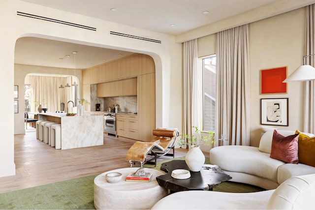 living room with light wood-style floors, arched walkways, and plenty of natural light