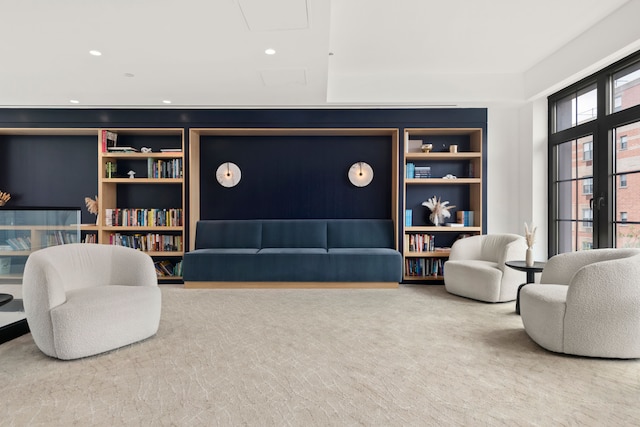 sitting room with carpet floors, built in shelves, and recessed lighting