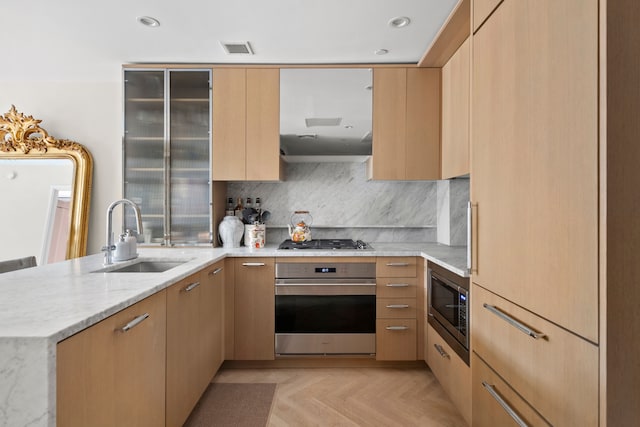 kitchen with appliances with stainless steel finishes, modern cabinets, a sink, and light stone counters