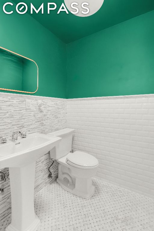 bathroom with tile walls, sink, tile patterned floors, and toilet