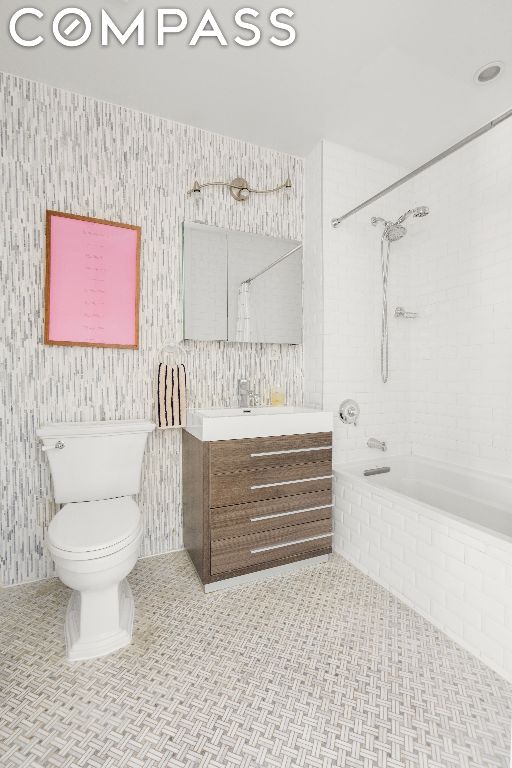 full bathroom featuring tiled shower / bath, vanity, tile patterned floors, and toilet