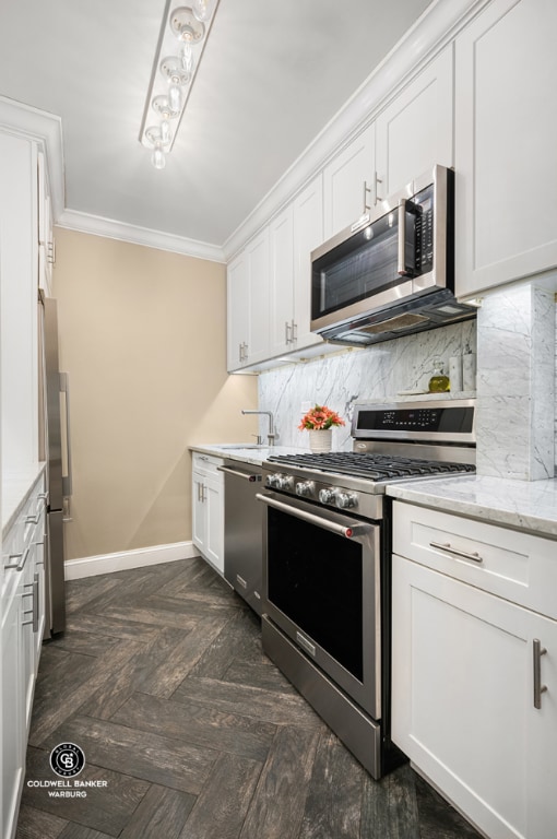 kitchen featuring appliances with stainless steel finishes, white cabinets, crown molding, dark parquet flooring, and light stone counters