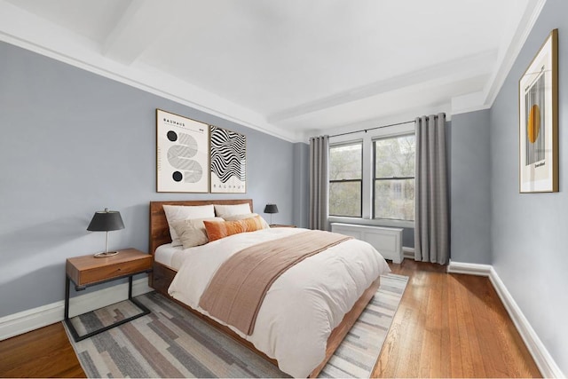 bedroom with crown molding, hardwood / wood-style floors, radiator heating unit, and beamed ceiling