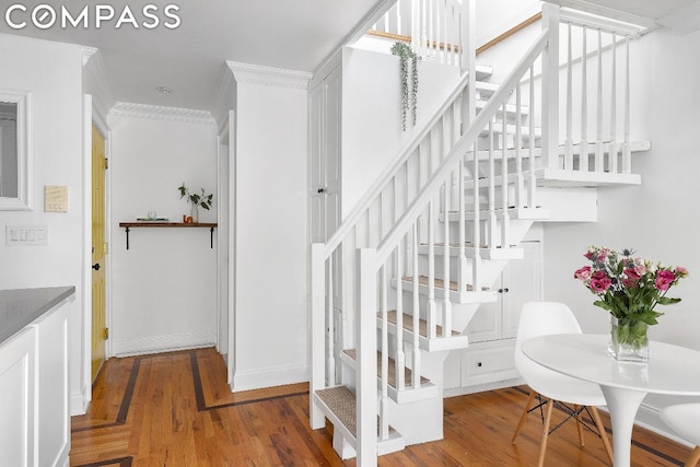 stairway with hardwood / wood-style flooring and crown molding