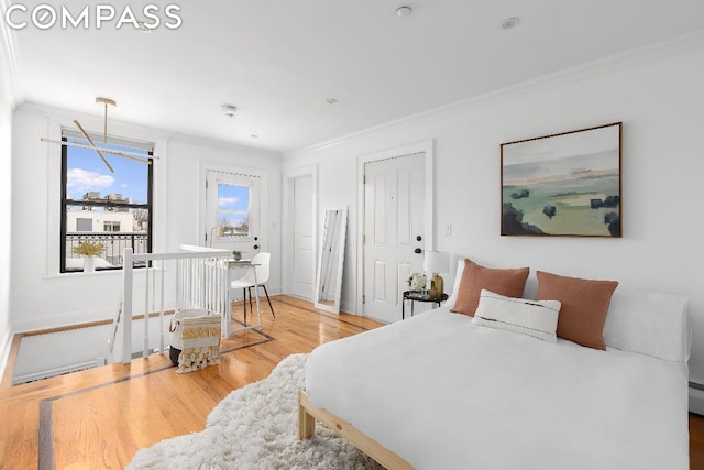 bedroom featuring a baseboard heating unit, hardwood / wood-style flooring, and ornamental molding