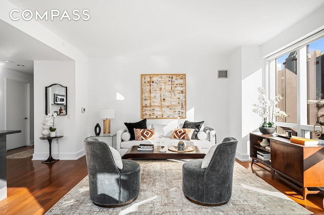 living area with visible vents, baseboards, and wood finished floors