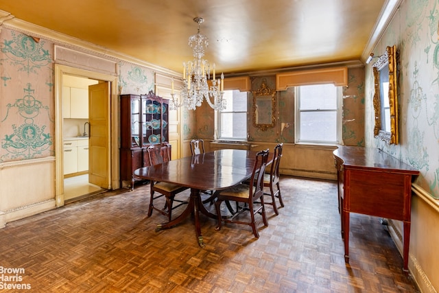 dining area with a notable chandelier, baseboard heating, ornamental molding, and wallpapered walls