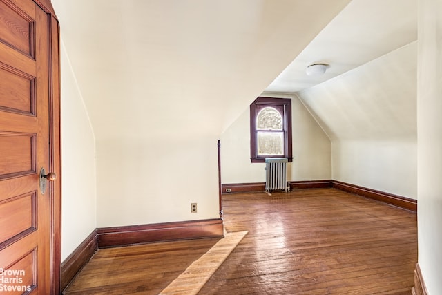 additional living space featuring lofted ceiling, radiator heating unit, and dark hardwood / wood-style floors