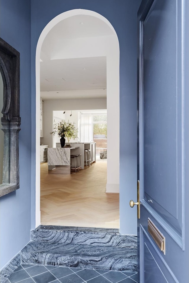 hall with arched walkways and wood finished floors