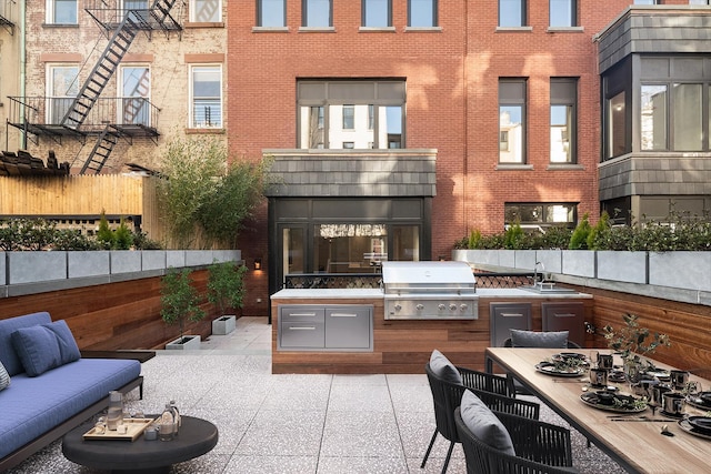 view of patio featuring a sink, an outdoor kitchen, a grill, and fence