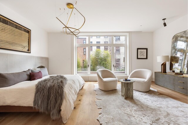 living area with light hardwood / wood-style flooring, lofted ceiling, and an inviting chandelier