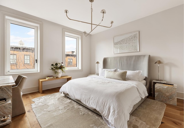 bedroom featuring multiple windows, baseboards, and wood finished floors